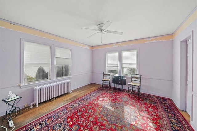 interior space with radiator heating unit, ceiling fan, and wood-type flooring