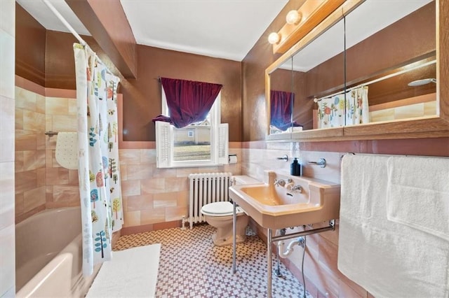 full bathroom featuring sink, radiator heating unit, shower / bath combination with curtain, toilet, and tile walls