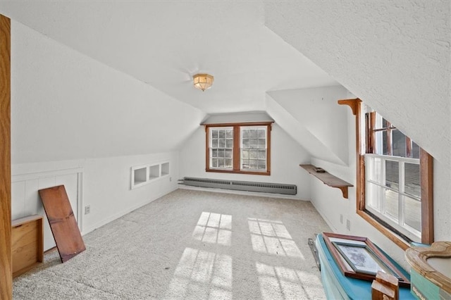 additional living space with baseboard heating, light carpet, and vaulted ceiling