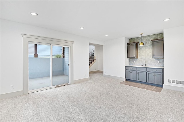 unfurnished living room with sink and light colored carpet