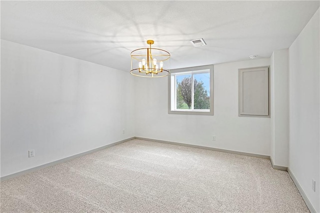 spare room featuring carpet and a notable chandelier