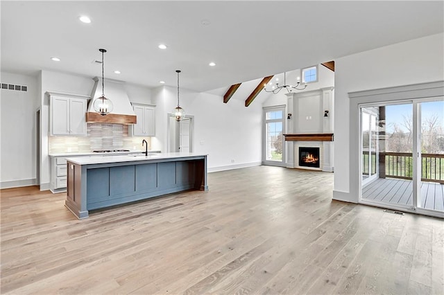 kitchen featuring a healthy amount of sunlight, a large island, hanging light fixtures, and light wood-type flooring