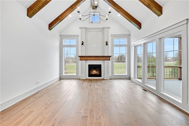 unfurnished living room with beam ceiling, an inviting chandelier, high vaulted ceiling, light hardwood / wood-style floors, and a tiled fireplace