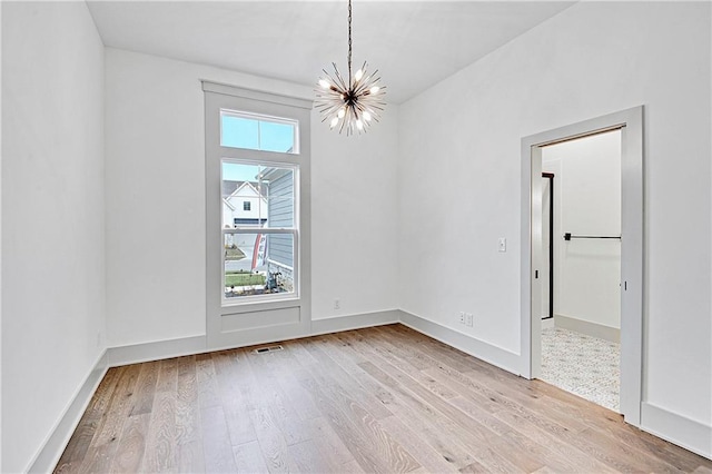 spare room with light hardwood / wood-style flooring and a notable chandelier