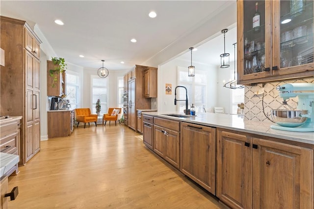 kitchen featuring pendant lighting, light hardwood / wood-style floors, sink, and tasteful backsplash