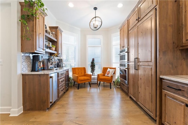 kitchen featuring backsplash, light hardwood / wood-style floors, decorative light fixtures, and ornamental molding