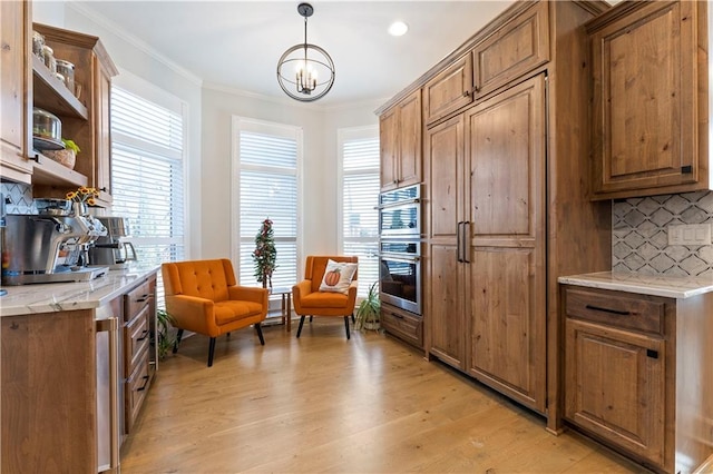 kitchen with backsplash, plenty of natural light, light hardwood / wood-style floors, and decorative light fixtures