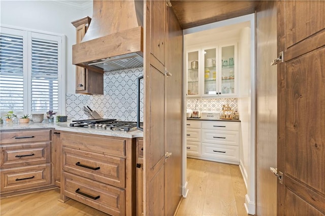 kitchen with premium range hood, decorative backsplash, light hardwood / wood-style floors, and stainless steel gas cooktop