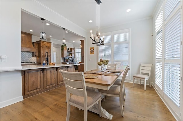 dining area featuring crown molding, a notable chandelier, and light wood-type flooring