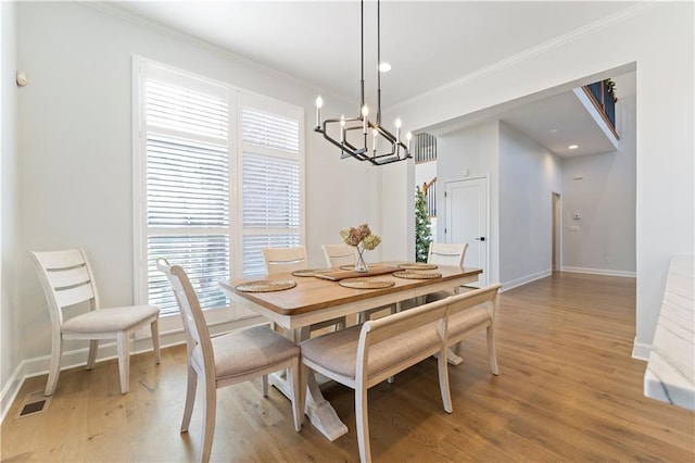 dining room with light hardwood / wood-style floors, crown molding, and a notable chandelier