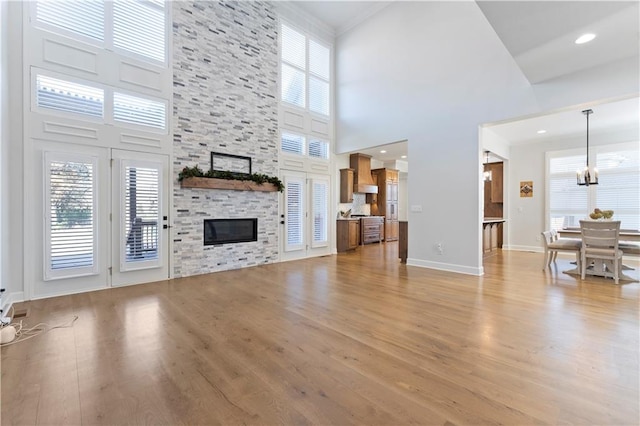 unfurnished living room featuring wood-type flooring, a towering ceiling, and a stone fireplace