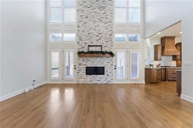 unfurnished living room with a stone fireplace, plenty of natural light, and a high ceiling