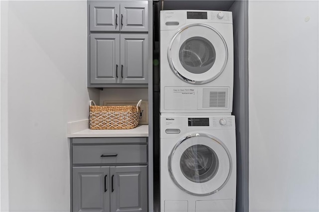 laundry room featuring cabinets and stacked washer and clothes dryer