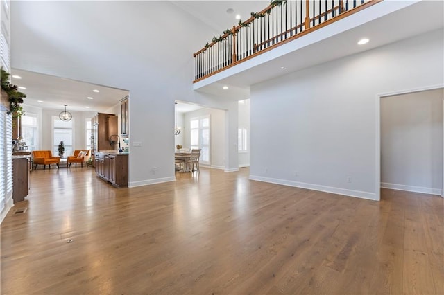 unfurnished living room featuring hardwood / wood-style floors, a towering ceiling, and sink