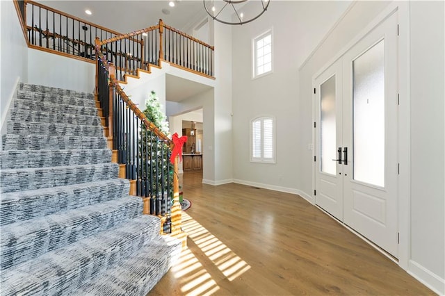 entryway featuring hardwood / wood-style floors, french doors, an inviting chandelier, and a high ceiling