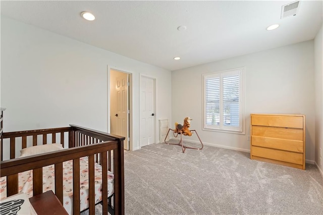 carpeted bedroom featuring a nursery area