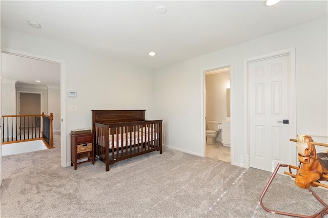 bedroom with connected bathroom, a nursery area, and light colored carpet