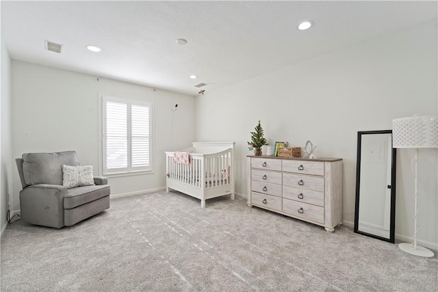 bedroom with a crib and light colored carpet