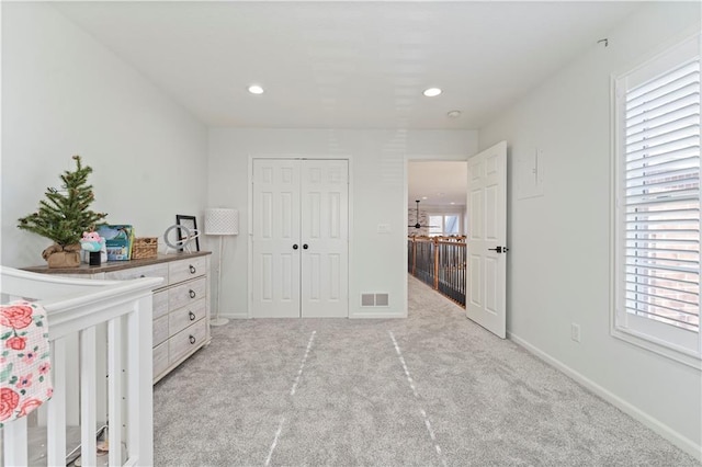 unfurnished bedroom with multiple windows, a closet, and light colored carpet