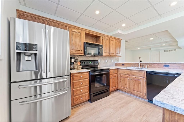 kitchen featuring a drop ceiling, black appliances, sink, decorative backsplash, and light hardwood / wood-style floors