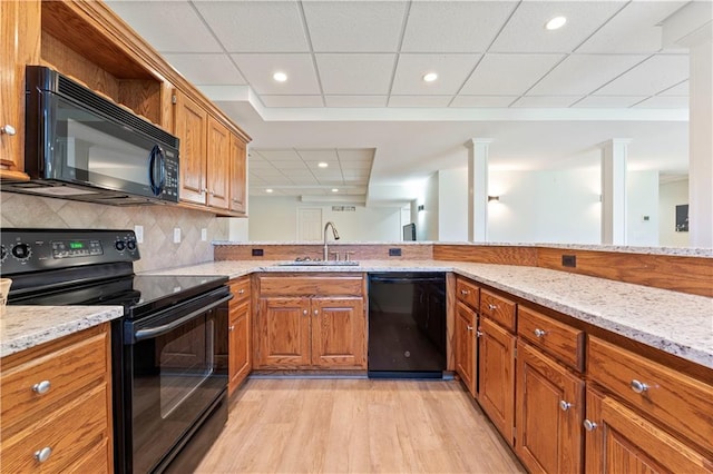 kitchen featuring decorative backsplash, light wood-type flooring, light stone counters, sink, and black appliances