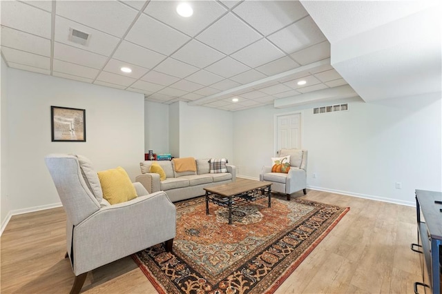 living room featuring a paneled ceiling and light wood-type flooring