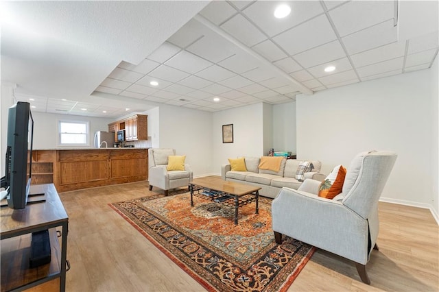 living room with a paneled ceiling and light hardwood / wood-style flooring