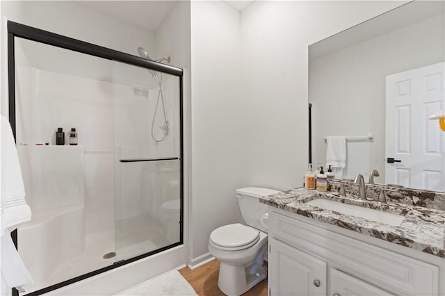 bathroom with hardwood / wood-style flooring, vanity, toilet, and a shower with shower door