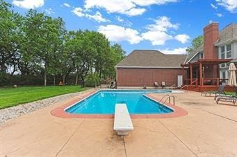 view of swimming pool featuring a diving board and a patio area