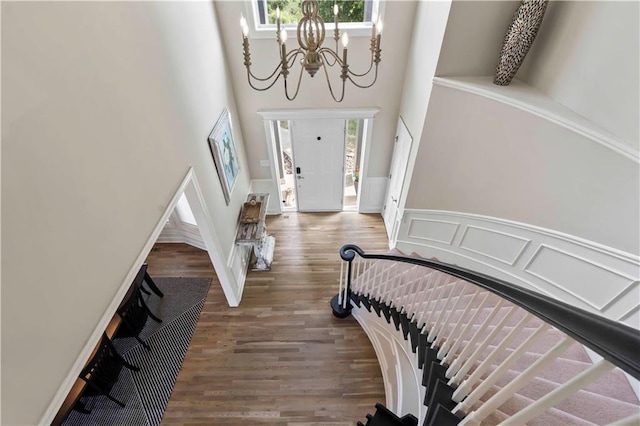 foyer entrance with dark hardwood / wood-style floors, a towering ceiling, and a chandelier