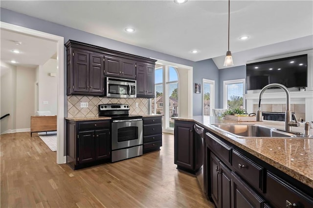 kitchen featuring dark brown cabinetry, sink, hanging light fixtures, light hardwood / wood-style flooring, and appliances with stainless steel finishes