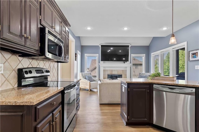 kitchen featuring dark brown cabinets, a tile fireplace, stainless steel appliances, and hanging light fixtures