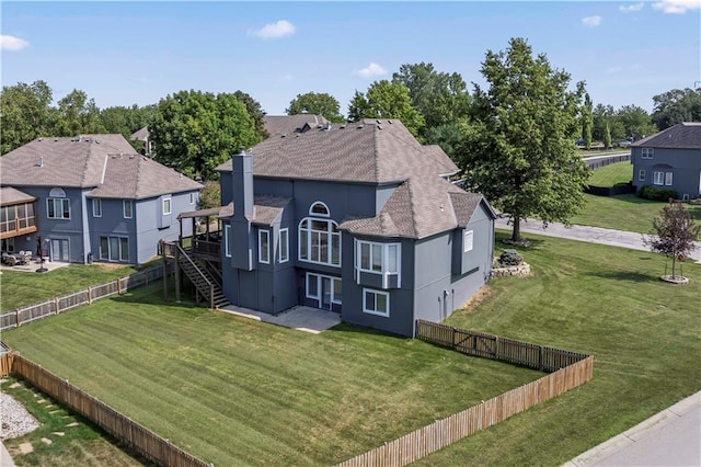 back of property with a wooden deck and a lawn