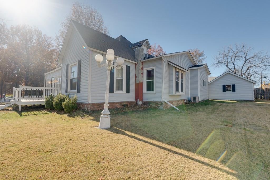 view of front of home with a front yard, central AC, and a deck