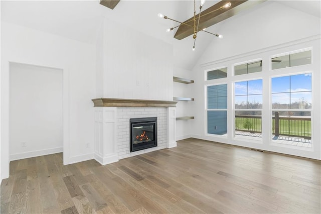 unfurnished living room with high vaulted ceiling, wood finished floors, visible vents, baseboards, and a brick fireplace