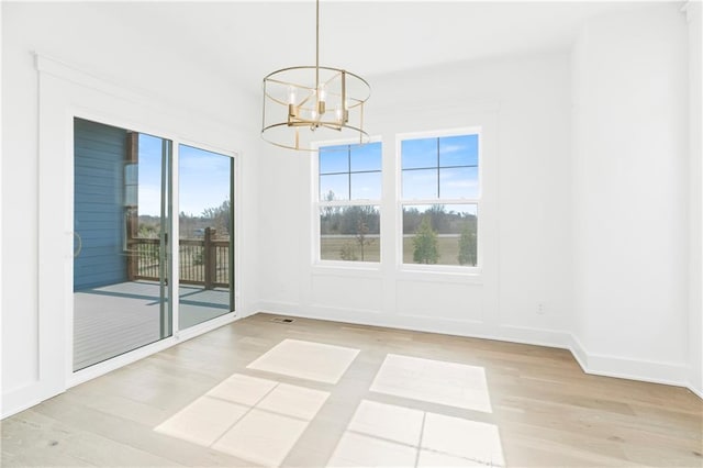 empty room with baseboards, wood finished floors, and a notable chandelier