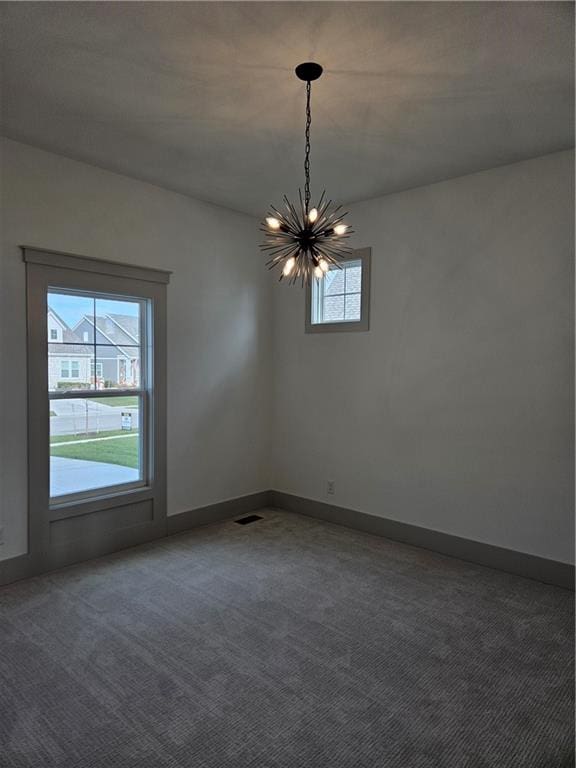 unfurnished room featuring carpet flooring, a healthy amount of sunlight, and a chandelier