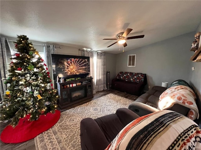 living room featuring ceiling fan, vaulted ceiling, and a fireplace