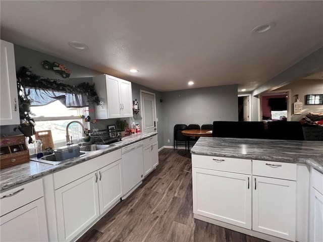 kitchen with sink, dark wood-type flooring, dishwasher, white cabinetry, and dark stone countertops