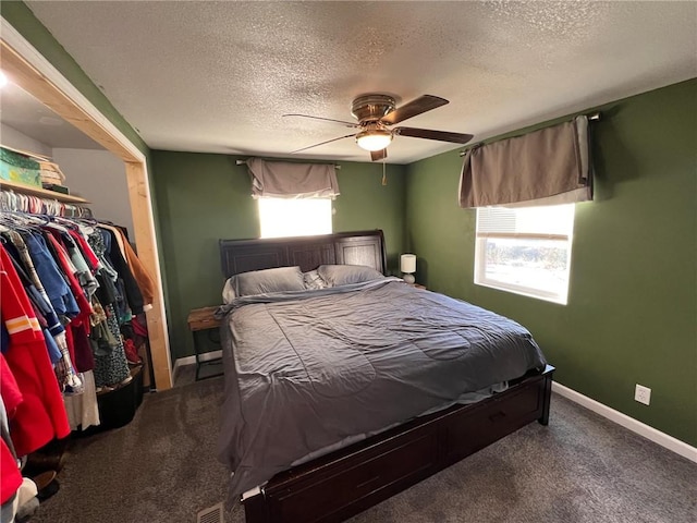 bedroom with ceiling fan, carpet flooring, and a textured ceiling