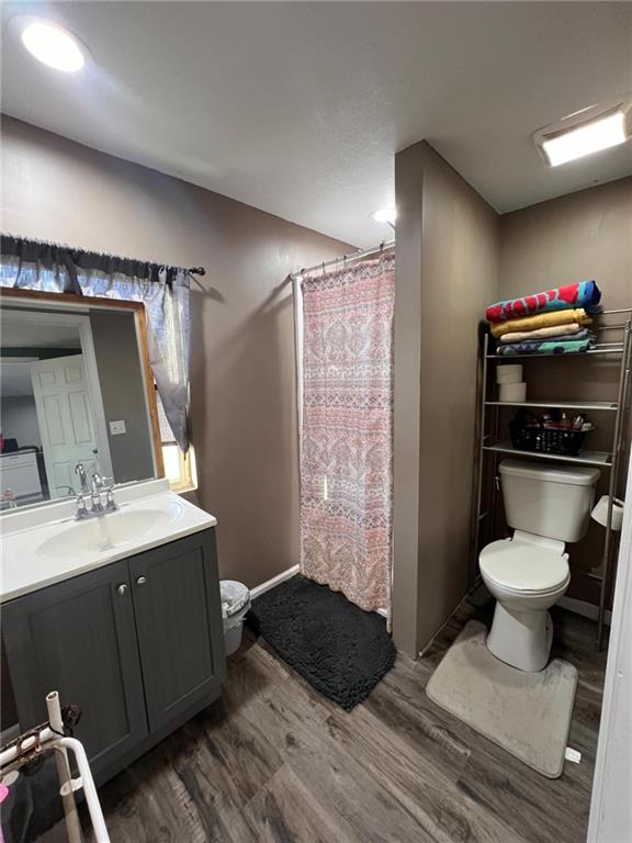 bathroom featuring hardwood / wood-style flooring, vanity, a shower with curtain, and toilet