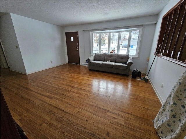 unfurnished living room with wood-type flooring and a textured ceiling