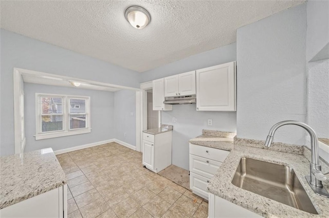 3612 College Ave, Kansas City, MO 64128 - kitchen with white cabinetry, light stone countertops, sink, and a textured ceiling
