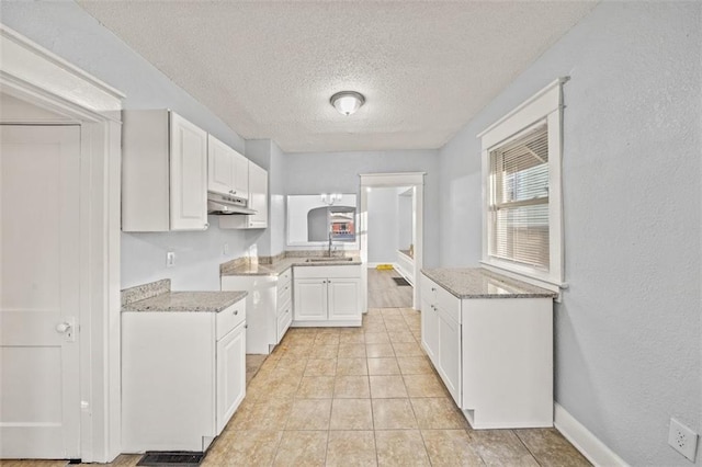 3612 College Ave, Kansas City, MO 64128 - kitchen with sink, light stone countertops, a textured ceiling, white cabinets, and light tile patterned flooring