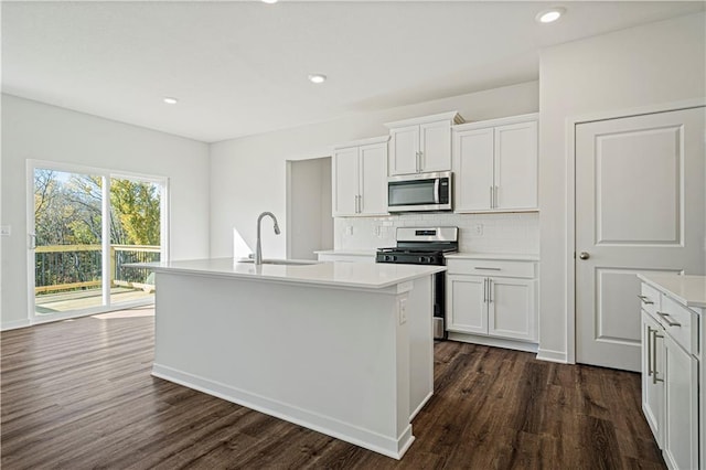 kitchen with dark wood-type flooring, sink, an island with sink, appliances with stainless steel finishes, and white cabinetry