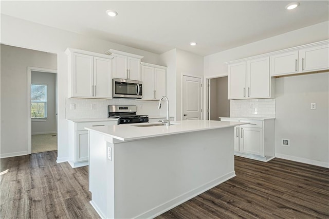 kitchen with dark wood-type flooring, white cabinets, a center island with sink, tasteful backsplash, and stainless steel appliances