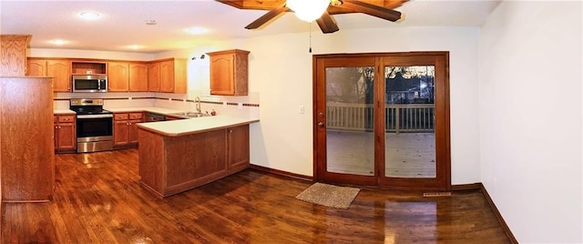 kitchen with sink, dark hardwood / wood-style floors, ceiling fan, appliances with stainless steel finishes, and kitchen peninsula