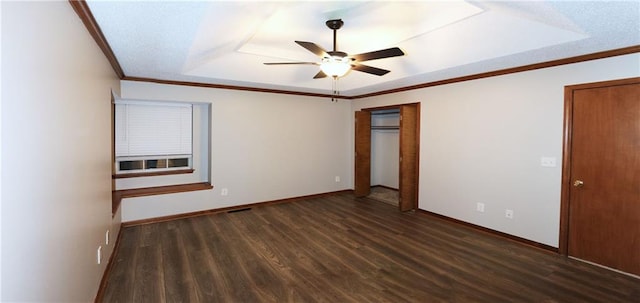 unfurnished bedroom featuring dark hardwood / wood-style flooring, a tray ceiling, ceiling fan, and crown molding