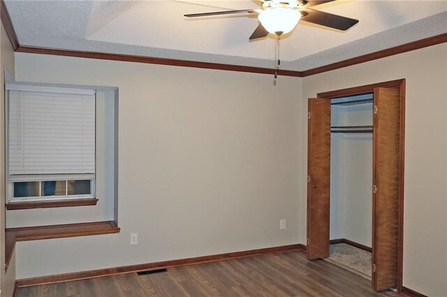 unfurnished bedroom featuring dark wood-type flooring, ceiling fan, ornamental molding, a textured ceiling, and a closet