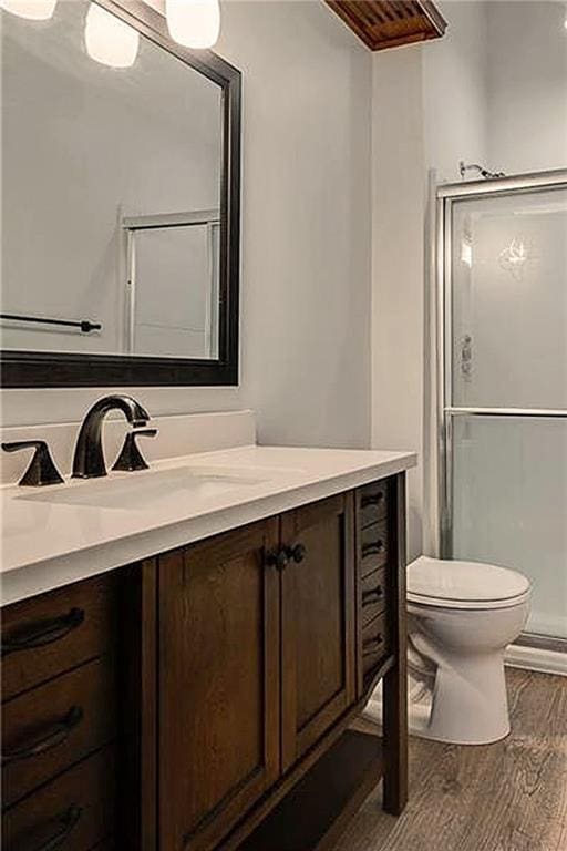 bathroom featuring vanity, toilet, an enclosed shower, and wood-type flooring